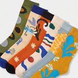 A set of six crew socks in assorted colors with abstract and artistic patterns, arranged diagonally on a light gray background.