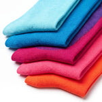 A stack of folded knit socks in a bright gradient of colors, including light blue, medium blue, purple, magenta, pink, and orange, on a white background.