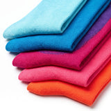 A stack of folded knit socks in a bright gradient of colors, including light blue, medium blue, purple, magenta, pink, and orange, on a white background.