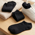 Black ankle socks on a wooden surface with a white sneaker.