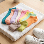 Colorful socks arranged on a white textured mat with white sneakers beside them.