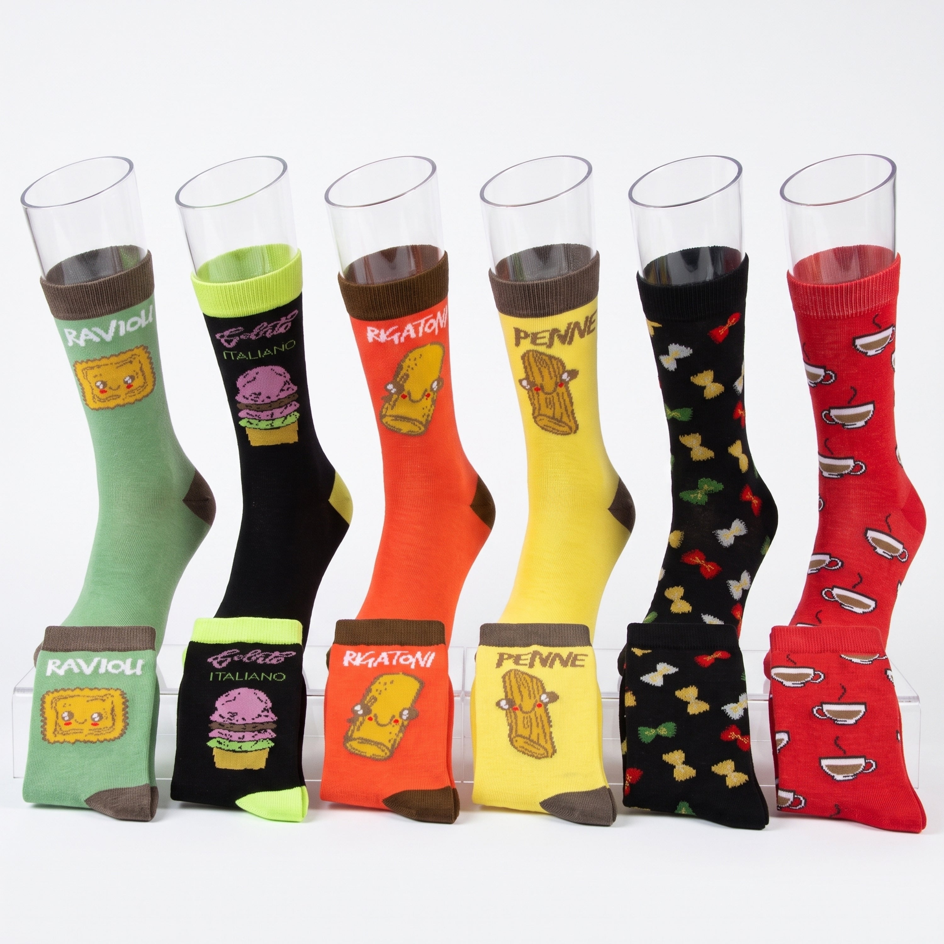 Six pairs of novelty socks displayed on clear plastic cups against a white background. The socks feature funny cartoon illustrations and Italian-themed names: ravioli, pizza, pasta, chocolate, bowties, and coffee cups.