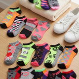 Colorful socks with various patterns on a wooden surface next to white sneakers.