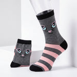 A pair of gray crew socks with a cute cartoon cat face and pink and black stripes, displayed on a white studio background with one sock on a mannequin leg and the other standing beside it.