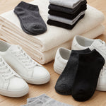 White sneakers with black and gray socks on a wooden floor