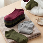 Stack of colorful socks on a towel with a white shoe nearby