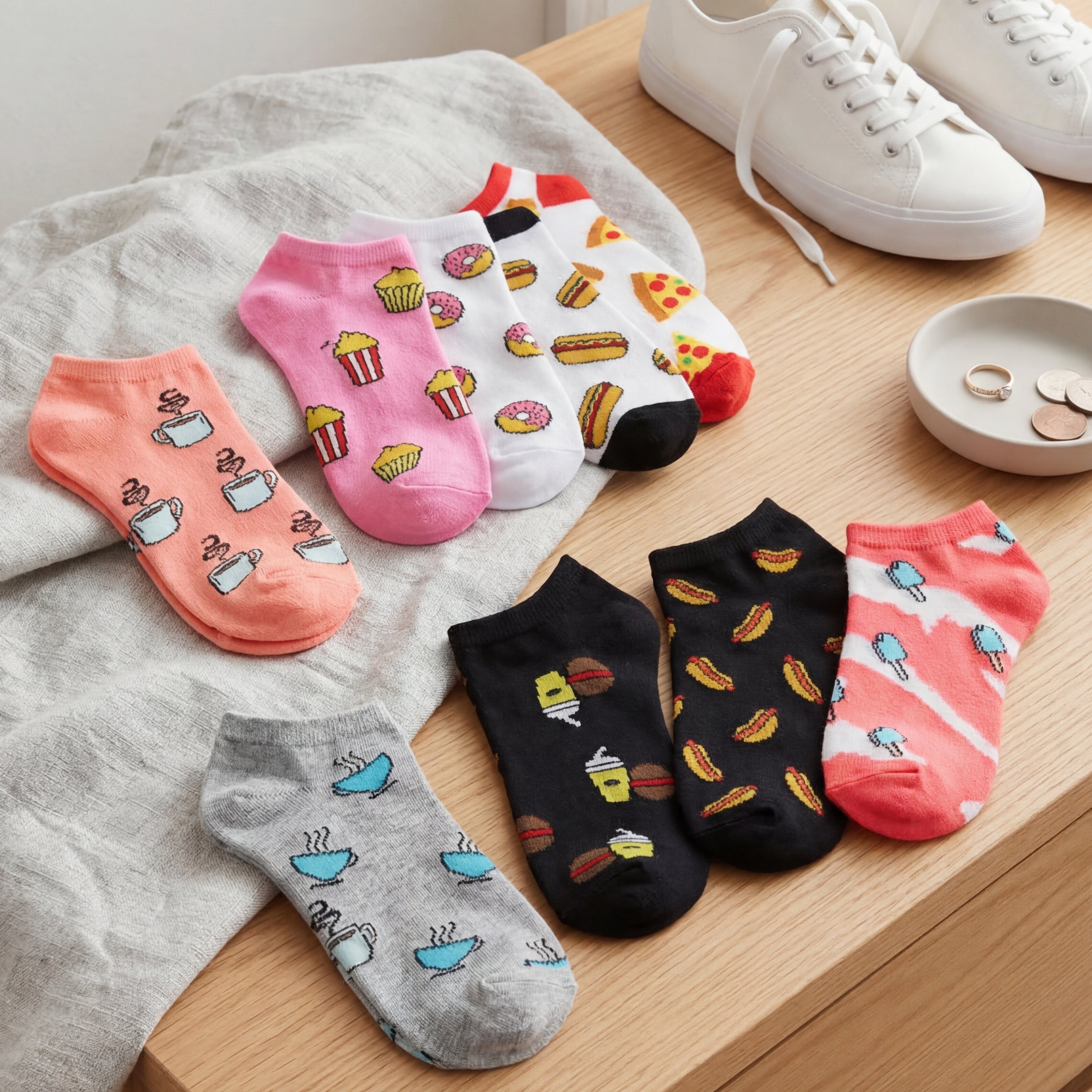 Set of colorful patterned socks on a wooden surface with white sneakers.