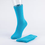 A bright turquoise blue crew sock displayed on a clear mannequin leg, with a matching folded sock placed beside it on a clean white studio background.