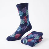 A pair of navy blue crew socks with a colorful striped and wavy geometric pattern, shown with one sock worn on a foot form and the other folded on a white background.