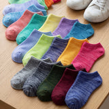 Colorful socks arranged on a wooden surface with white shoes in the background.