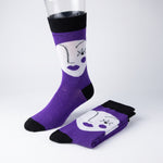Purple crew socks with a white cartoon face graphic and black toe, heel, and cuff, displayed on a mannequin leg with one folded pair on a light gray background.