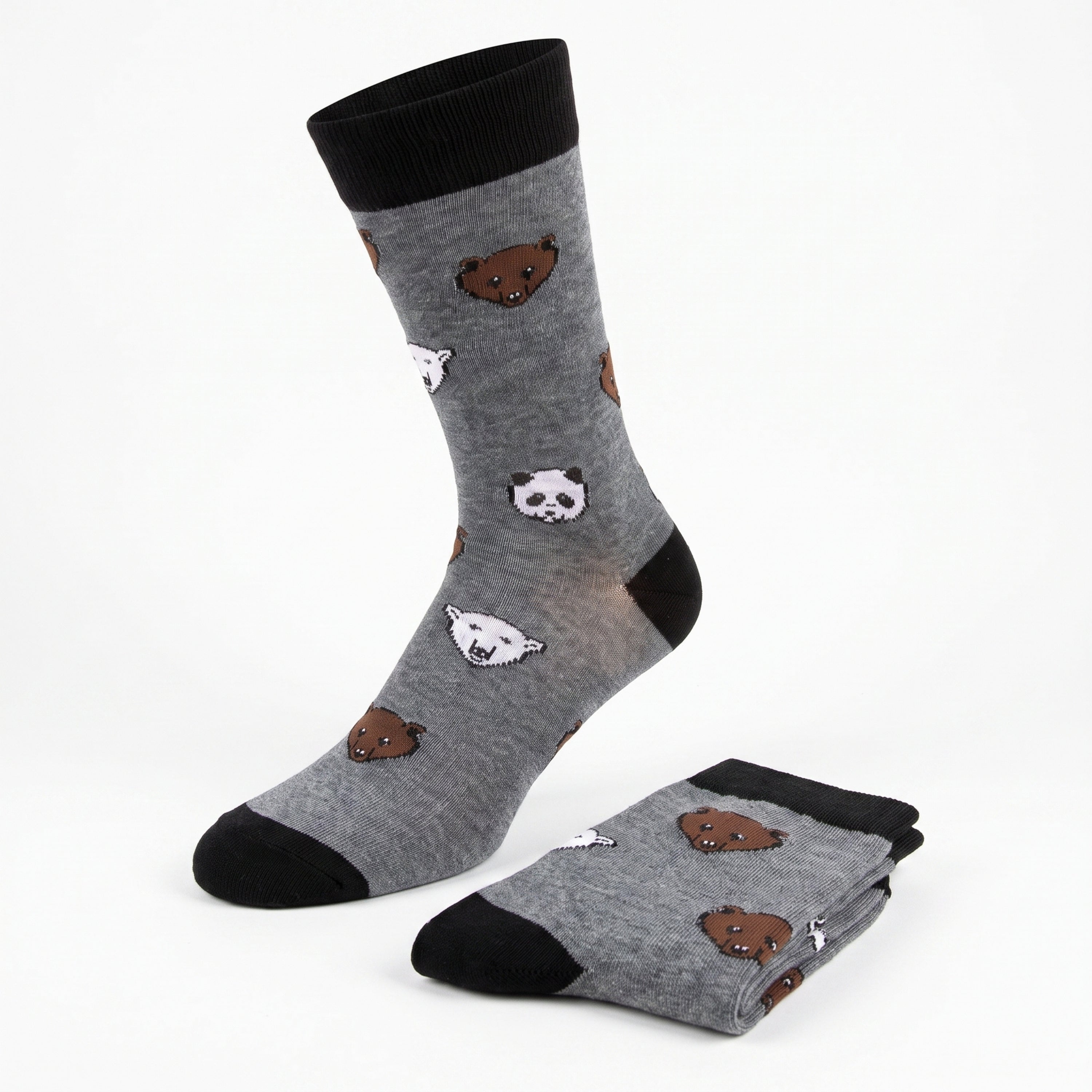A pair of gray crew socks with black cuffs, heels, and toes, featuring a playful pattern of cartoon polar bear and panda faces, shown with one sock standing upright and the other folded on a white background.