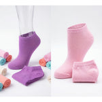 Purple and pink socks on a white background with rolled-up socks in the foreground.