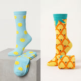 Two pairs of socks with pineapple and smiley face patterns on a light gray background.