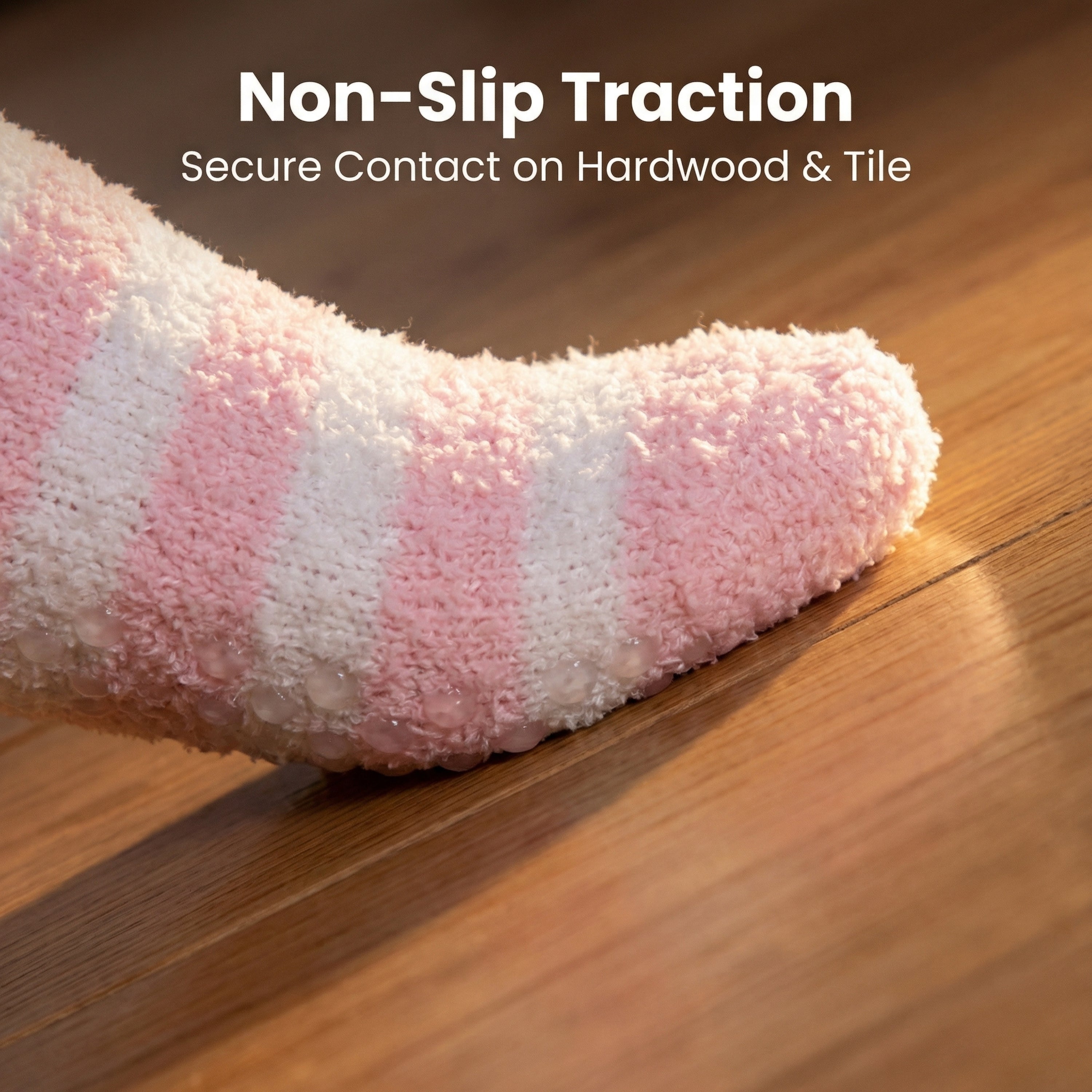 Pink and white striped sock on a wooden floor with text 'Non-Slip Traction' and 'Secure Contact on Hardwood & Tile'.