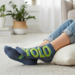 Person wearing socks with 'YOLO' text in a living room setting