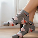 Gray socks with cat and flower pattern worn by a person indoors.