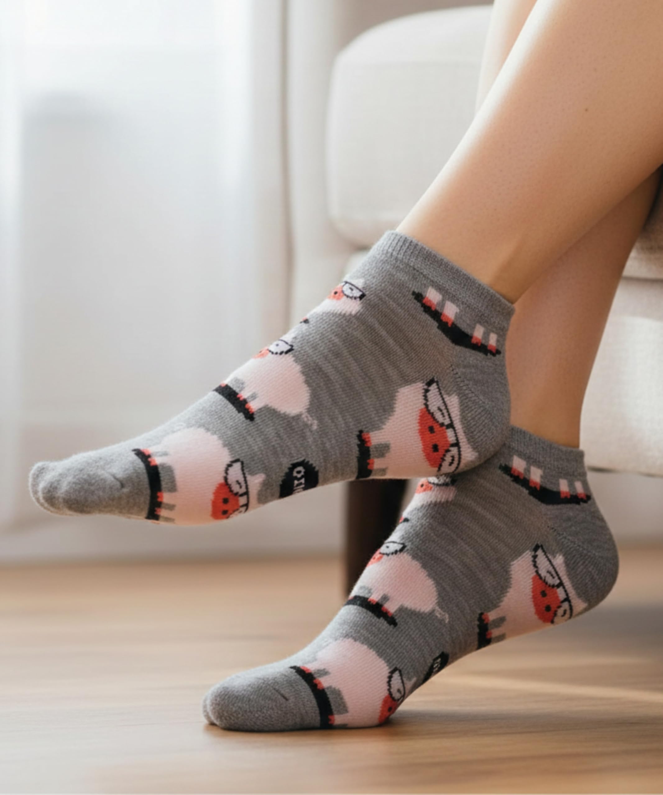 Gray socks with cat and flower pattern worn by a person indoors.