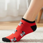 Red socks with black and white pattern worn by a person on a light carpet.