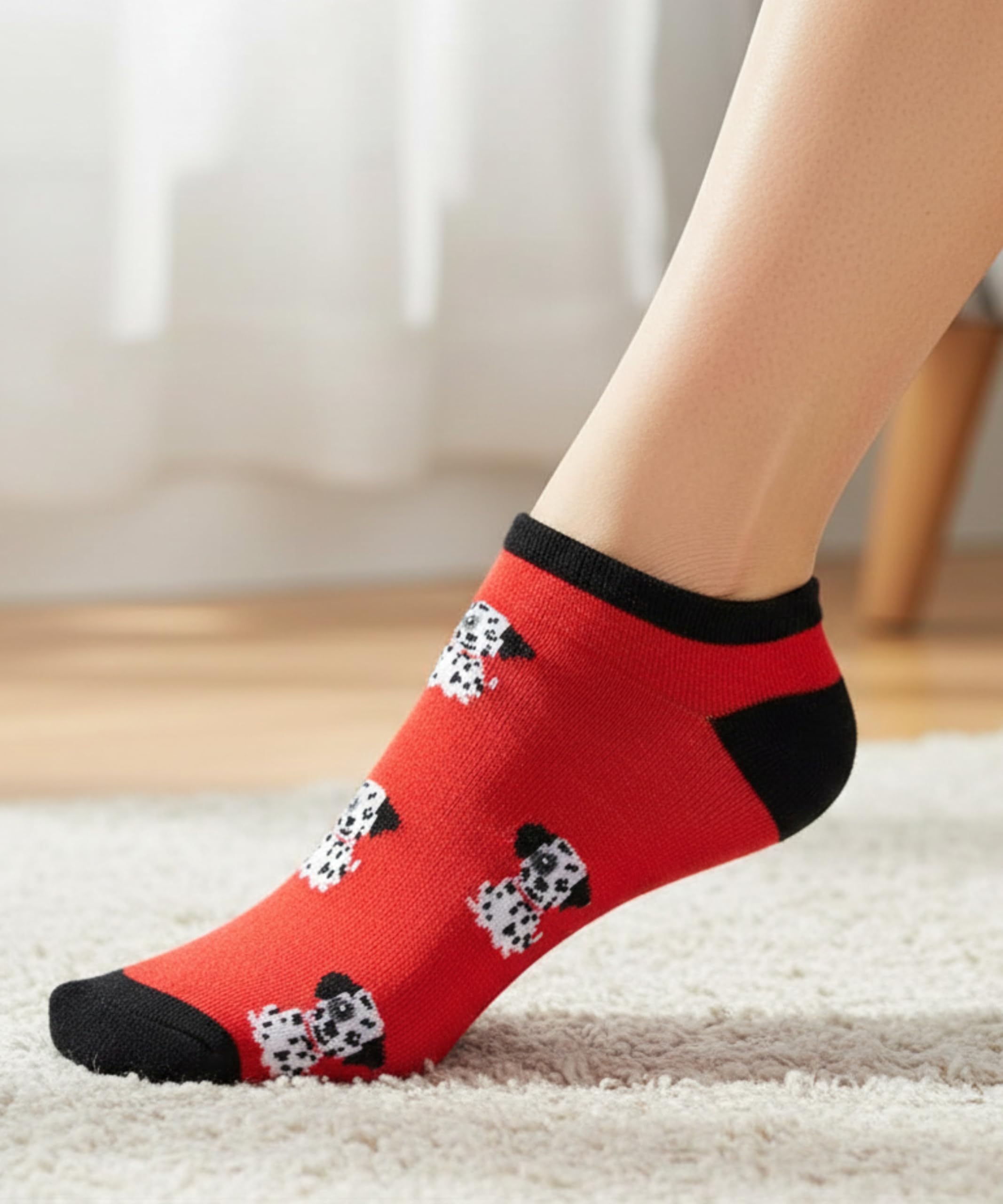 Red socks with black and white pattern worn by a person on a light carpet.