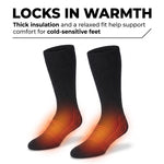 A pair of black ribbed crew socks shown on a white background with marketing text at the top reading 'LOCKS IN WARMTH' and smaller copy about thick insulation and comfort for cold-sensitive feet. The socks have a glowing orange heat-map style graphic over the lower legs and feet to indicate warmth.