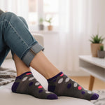 Person wearing dark gray socks with colorful polka dots in a home setting.