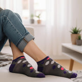 Person wearing dark gray socks with colorful polka dots in a home setting.
