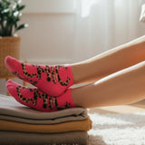 Person wearing pink socks with leopard print text on a carpeted floor.