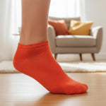 Orange sock worn by a person indoors with a blurred background of a living room.