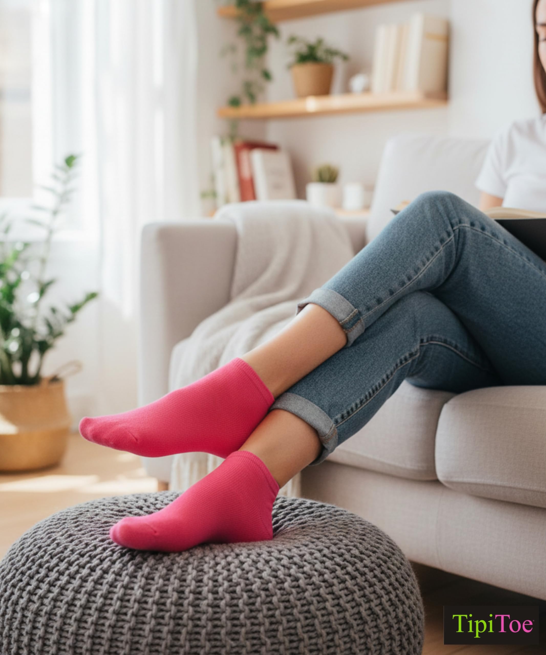 Person wearing pink socks and blue jeans sitting on a ottoman in a living room.
