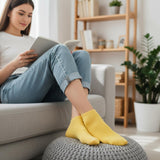 Woman sitting on a couch with yellow socks, reading a book in a cozy living room.