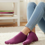 Person wearing purple socks and light blue jeans on a carpeted floor.