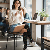 Woman sitting at a cafe table wearing colorful knee-high socks, holding a cup.