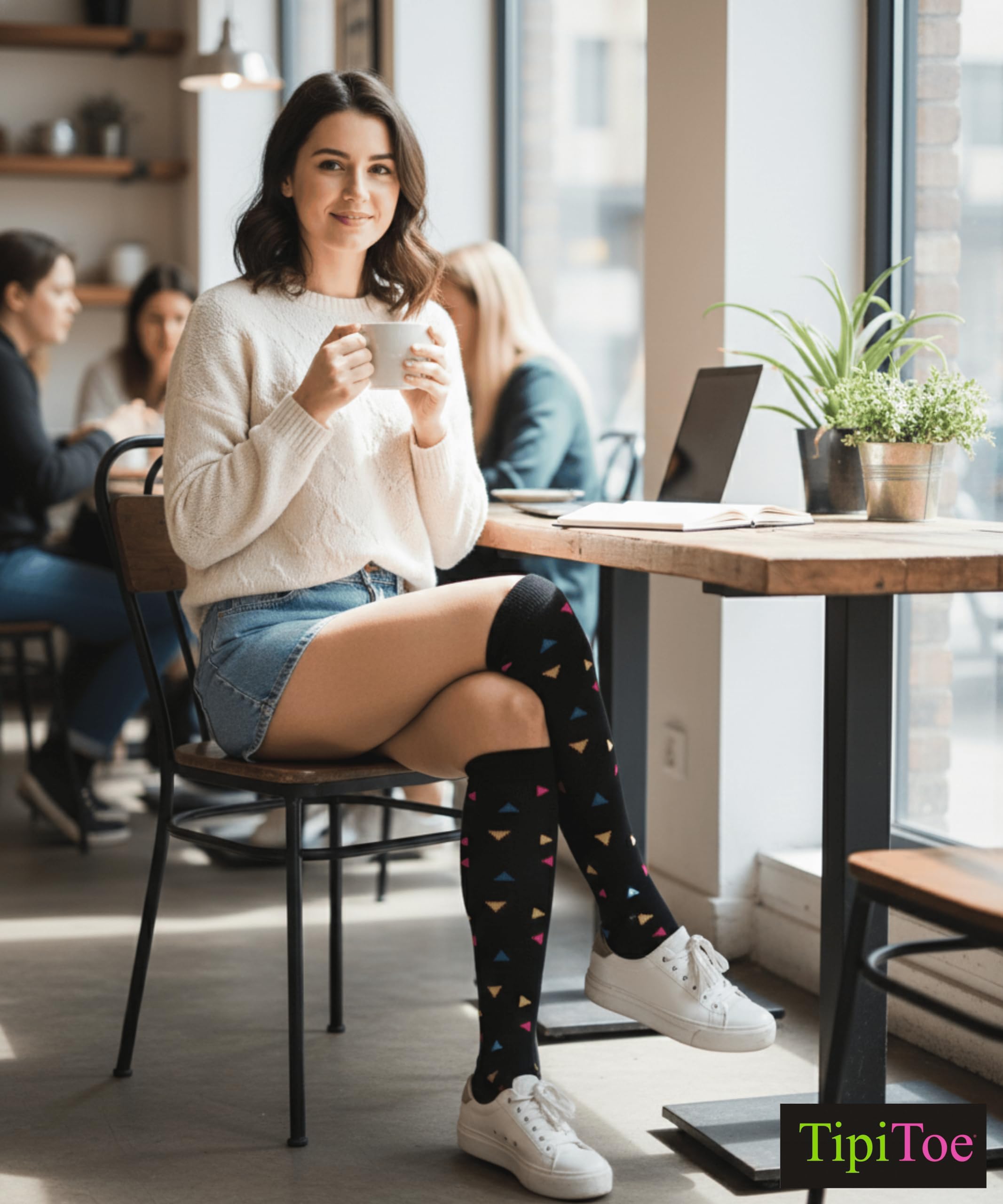 Woman sitting at a cafe table wearing colorful knee-high socks, holding a cup.