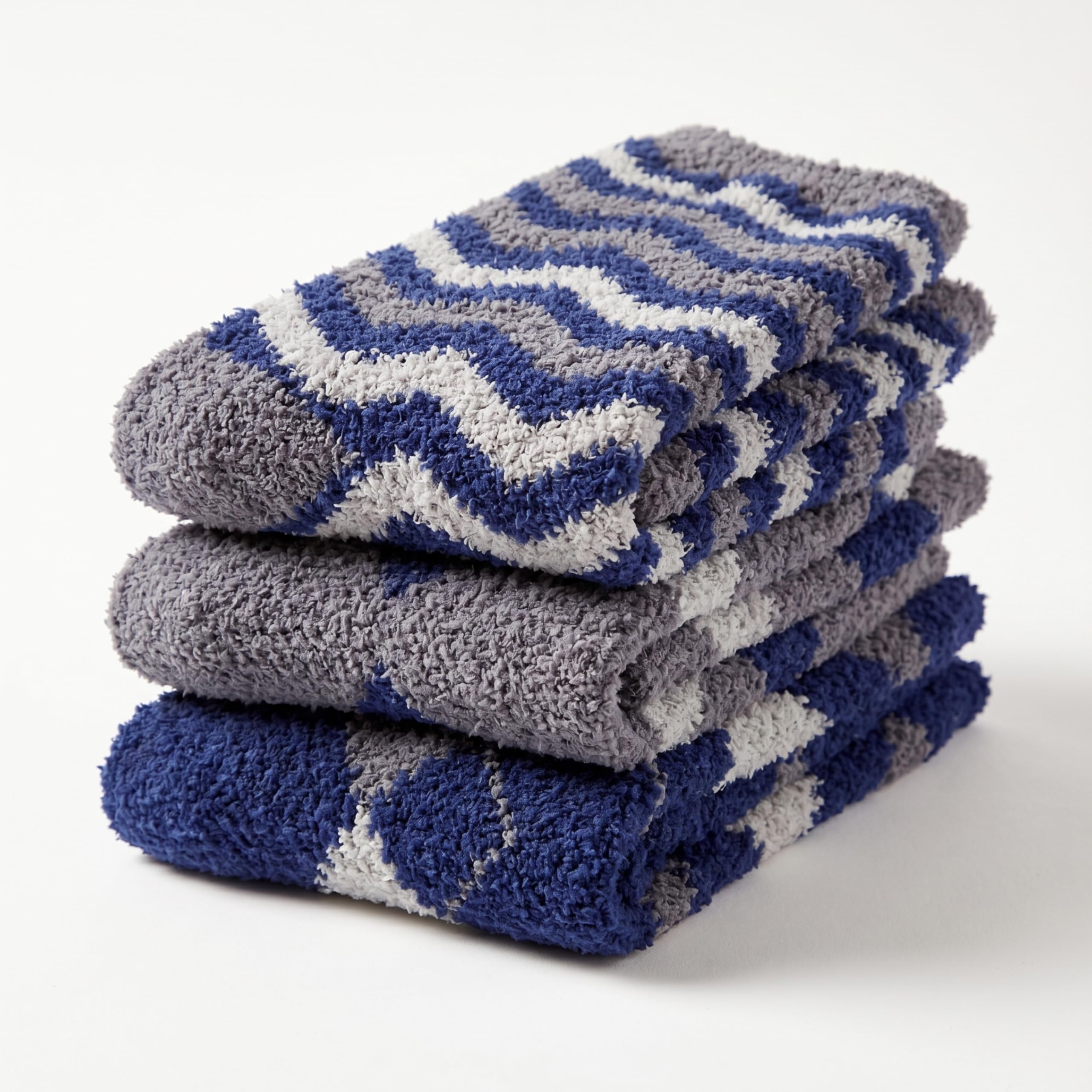 Three folded plush bath towels stacked on a white background, featuring a blue, gray, and white chevron pattern.