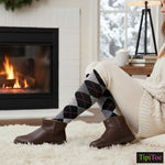 Person wearing brown boots and argyle socks in a cozy living room with a fireplace.