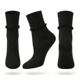 Three black ankle socks with a ruffled trim at the ribbed cuff, shown from different angles on a white background.