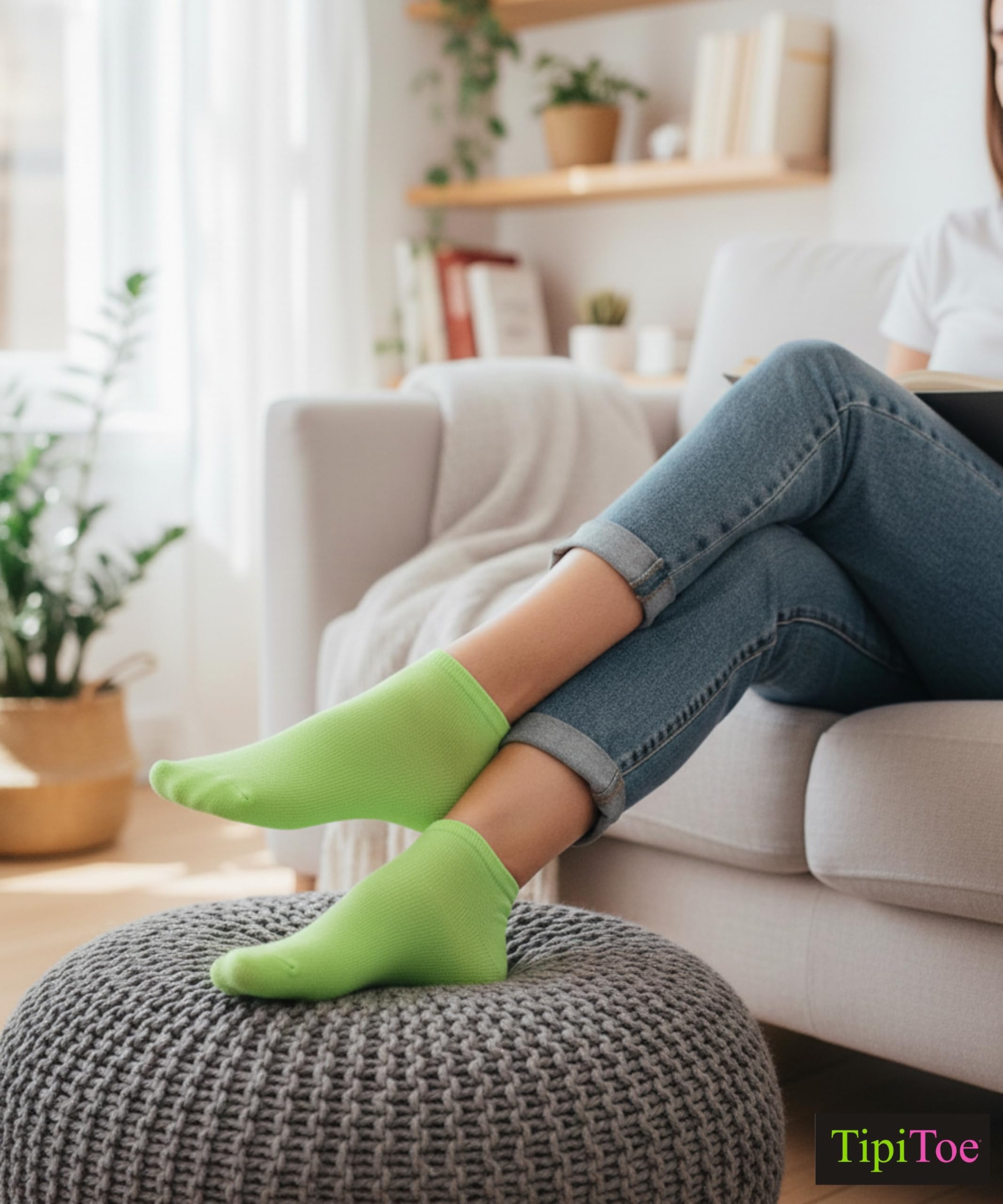 Person wearing bright green socks and blue jeans sitting on a ottoman in a living room.
