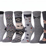 Six pairs of patterned crew socks displayed side by side against a plain white background. The socks feature various designs including snowflakes, geometric patterns, animal motifs, and argyle, in shades of gray, black, and beige.