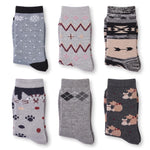 Six pairs of folded crew socks arranged in a 2x3 grid on a white background. The socks feature various patterns including snowflakes, zigzags, argyle, paw prints, and cartoon dogs in shades of gray, black, beige, and pink.