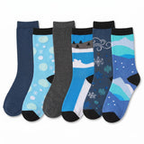 Six pairs of children's crew socks arranged in a fan shape on a white background. The socks feature various winter-themed patterns including snowflakes, snow caps, and mountain landscapes in shades of blue, gray, and black.