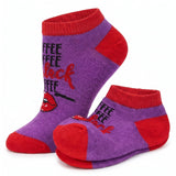 A pair of low-cut ankle socks in purple and red with a graphic design. The design features the word 'COFFEE' repeated in black, stylized red script reading 'black coffee', and a graphic of red lips with a black line drawing.