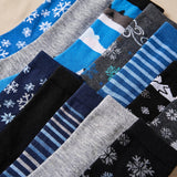 A close-up arrangement of multiple pairs of socks in different colors and patterns, including blue, gray, black, navy, and white snowflake and stripe designs.