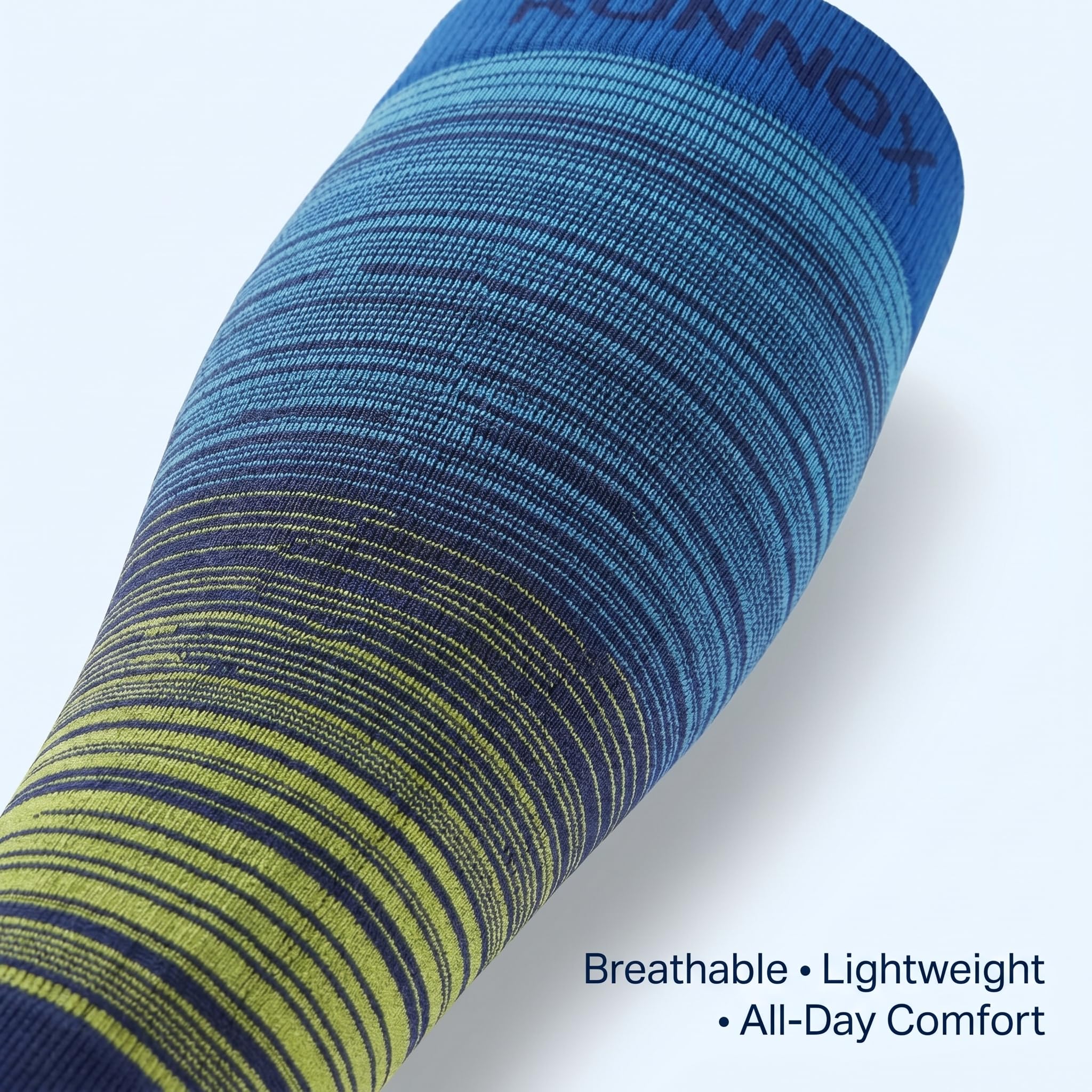 A close-up of a blue and navy compression sleeve with yellow-green striped knit detailing near the lower section, shown on a light gray background with text reading 'Breathable • Lightweight • All-Day Comfort'.