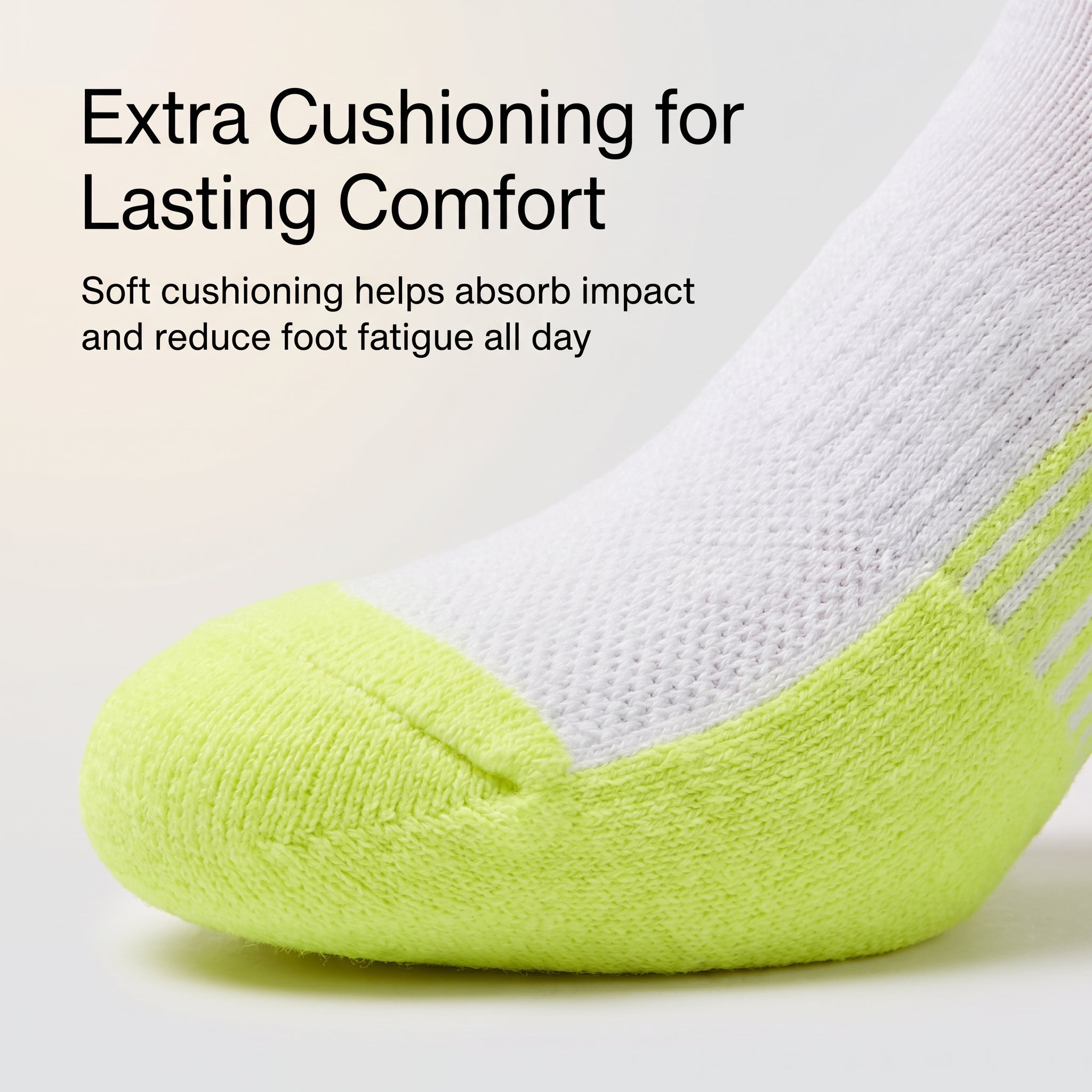 A close-up of a single athletic sock with a bright neon yellow-green toe and heel, white knit upper, and three thin dark stripes near the cuff. Text on the image reads: 'Extra Cushioning for Lasting Comfort' and 'Soft cushioning helps absorb impact and reduce foot fatigue all day.