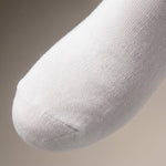 A close-up of a white knit sock with a ribbed toe, shown against a neutral beige background.