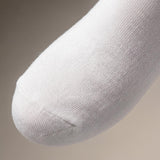 A close-up of a white knit sock with a ribbed toe, shown against a neutral beige background.