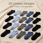 A flat-lay arrangement of twenty low-cut socks in assorted colors and textures, including black, light blue, medium blue, and heather gray, on a beige fabric background. Text at the top reads '20 Unique Designs Fun • Classy • Everyday Wear'.
