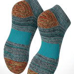 A pair of low-cut knit socks with a marled teal, brown, and orange pattern, featuring a solid teal ribbed heel and toe. The image includes marketing text at the top reading 'Cushioned Sole Comfort' and a light blue circular graphic at the bottom representing cushioning.