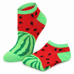 A pair of novelty low-cut socks with a watermelon print, featuring a red body with black seeds, a green striped rind, and bright green cuffs and toes, shown on a plain white background.
